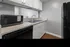 Modern kitchen with sleek black appliances, white cabinetry, and elegant countertops featuring a stylish gray backsplash.