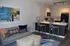 Contemporary living room and kitchen with stylish decor, featuring a comfy gray sofa, abstract art, and a modern breakfast bar.