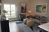 Inviting living room with modern gray sofa, stylish armchairs, vibrant artwork, and large window offering natural light.