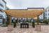 Elegant outdoor lounge with a modern wooden pergola, stylish seating, and lush greenery in a sophisticated apartment complex courtyard.