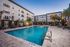 Luxurious apartment community featuring a sparkling outdoor pool, surrounded by elegant lounge chairs and lush palm trees, perfect for relaxation and leisure.