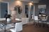 Modern apartment dining area featuring chic tables with white chairs, elegant decor, and stylish lighting in a contemporary setting.
