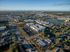 Vibrant aerial view of a modern apartment complex surrounded by lush greenery, expansive roads, and serene water bodies, offering a desirable urban lifestyle.