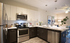 Modern apartment kitchen featuring stainless steel appliances, elegant cabinetry, and a stylish breakfast bar, leading to an inviting open-concept living space with chic decor.