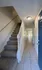 Bright entryway with elegant carpeted stairs and a welcoming hallway leading to sunlit rooms, showcasing modern tile flooring and a charming blue door.