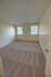 Bright and spacious bedroom with natural light streaming through large windows, featuring clean carpeted flooring.