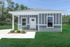 Charming single-story home with modern blue and white exterior, nestled amidst lush greenery, featuring a cozy front porch and elegant windows.
