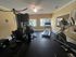Modern fitness center with state-of-the-art equipment, including a treadmill, elliptical, and strength training machine, overlooking a scenic outdoor pool area.