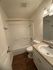 Inviting bathroom with elegant wood flooring, modern fixtures, and a sleek white bathtub for a refreshing retreat.