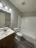 Modern bathroom with sleek vanity, pristine bathtub, and elegant lighting, featuring stylish wood flooring and contemporary design.