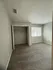 Bright and spacious bedroom with soft carpet flooring, neutral walls, and a large window providing natural light.