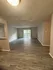 Spacious living area with elegant wood flooring, large window, and bright lighting, perfect for cozy gatherings.
