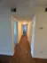 Inviting apartment hallway with warm wood flooring and soft lighting, leading to multiple rooms.