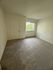 Bright room with soft carpeting, a window with garden view, and pristine white walls.