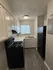 Cozy kitchen with modern black appliances, ample cabinetry, and sleek wood flooring, basking in natural light.