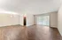Spacious open-concept living room featuring elegant hardwood flooring, large windows with vertical blinds, and soft ambient lighting.