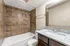 Elegant bathroom featuring a stylish granite countertop, modern fixtures, and a luxurious tiled bathtub area.
