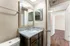 Modern bathroom with elegant granite countertops and a stylish vanity mirror, leading into a bright bedroom with sleek wooden flooring.