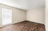 Bright and airy room with sleek hardwood flooring and large window inviting natural light.