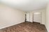 Spacious bedroom with elegant wood flooring, pristine beige walls, and a large closet offering ample storage.