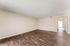 Spacious apartment interior featuring elegant hardwood flooring and an inviting passageway leading to well-lit rooms.
