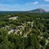Aerial view of a serene residential community nestled amidst lush greenery with a stunning mountain backdrop, offering tranquility and scenic beauty.