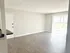 Bright and spacious living area with elegant laminate flooring and sliding glass doors leading to a serene outdoor view, perfect for modern living.