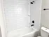 Modern bathroom featuring sleek white subway tiles, a chic black showerhead, and a pristine bathtub offering an inviting and relaxing space.
