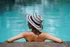 Serene poolside escape featuring a person in a wide-brimmed hat relaxing by crystal clear water, perfect for resort-style living.