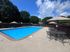 Inviting outdoor swimming pool with stylish patio seating and lush greenery under a clear blue sky.