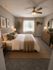Cozy bedroom with elegant decor featuring a plush bed, warm lighting, and large window with garden view.