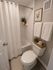 Elegant bathroom with modern white tiled shower, stylish fixtures, and cozy decor accents.