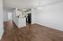 Bright open-concept apartment with sleek flooring, modern kitchen with black appliances, and inviting dining area under elegant lighting.