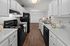 Modern kitchen with sleek white cabinetry, dark appliances, and elegant wood flooring, perfect for culinary creativity.