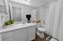 Elegant bathroom with sleek white cabinetry, a spacious countertop, and modern fixtures, complemented by lush green plants for a refreshing touch.