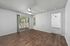 Bright and airy living room with sleek wooden floors, ceiling fan, and sliding doors opening to a charming balcony with lush views.