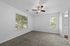 Bright and inviting bedroom with large windows, plush carpeting, and a modern ceiling fan.