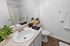 Contemporary bathroom with sleek vanity, stylish accessories, and elegant wood flooring.