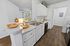 Elegant kitchen with white cabinetry, modern fixtures, and warm hardwood floors, featuring stylish fall decor and abundant natural light.