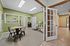 Inviting office space featuring modern design with a cozy seating area and a round table, accented by vibrant green walls and elegant French doors.