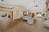 Spacious and inviting living area with elegant wooden flooring, plush seating, and abundant natural light from large windows overlooking a serene outdoor pool.