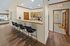 Inviting open kitchen space with wooden cabinetry, a sleek countertop breakfast bar, and stylish barstools, perfect for social gatherings.