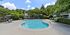 Inviting apartment complex pool area with scenic landscaping, loungers, and outdoor seating under vibrant umbrellas, perfect for relaxation and leisure.