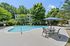 Inviting pool area with modern patio furniture and lush greenery, perfect for relaxation and leisure in a serene apartment complex.