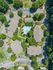 Aerial view of a serene apartment complex featuring lush green surroundings, a central swimming pool, and well-organized parking areas, offering a blend of comfort and nature.