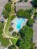 Aerial view of a serene apartment complex featuring a beautifully shaped pool surrounded by lush greenery and modern buildings, ideal for relaxation and leisure.
