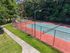 Inviting outdoor tennis court set amidst lush greenery, perfect for sports enthusiasts and leisure activities.