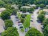 Lush aerial view of a welcoming apartment community with spacious parking, verdant landscaping, and charming residential buildings.