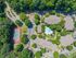 Aerial view of a vibrant apartment complex featuring lush greenery, a sparkling swimming pool, and a well-maintained tennis court.