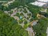 Aerial view of a picturesque apartment complex nestled in lush greenery, featuring a sparkling pool and vibrant tennis courts, ideal for active living.
